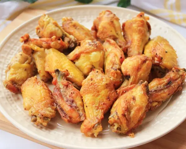 Alitas de pollo doradas y crujientes en un plato blanco.