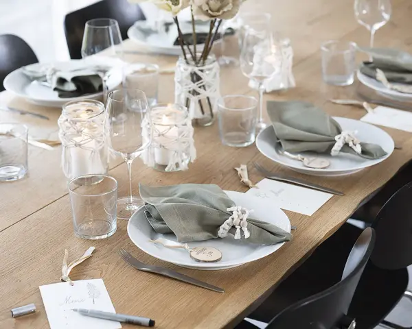 Vacker dukning med gröna servetter, ljus och blommor. Perfekt fest dekoration inspiration för ett stilrent hem.