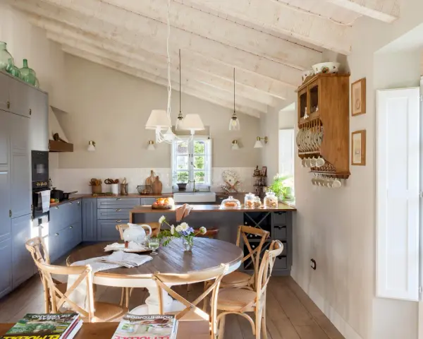 Cocina rústica y acogedora. Ideas para decorar casa vieja de pueblo con poco dinero. Techos de madera, muebles grises y mesa redonda.