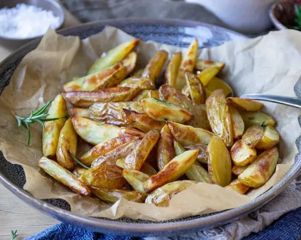 Klyftpotatis i airfryer, gyllene och krispiga, serverade med rosmarin. Perfekt tillbehör!