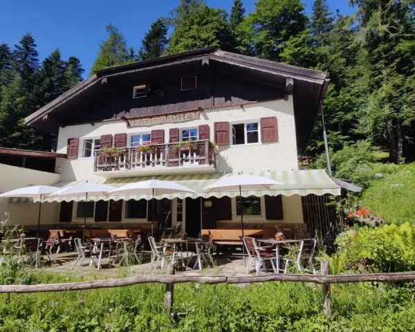 Rifugio alpino con tavoli all'aperto, ideale per rilassarsi dopo le ronzone passeggiate nel bosco.