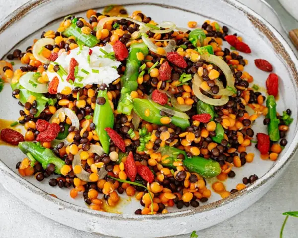 Bunter Linsensalat mit Spargel, Goji-Beeren und einem Klecks Joghurt. Ein köstliches Gericht, das zeigt, wie vielfältig Linsen Rezepte sein können.