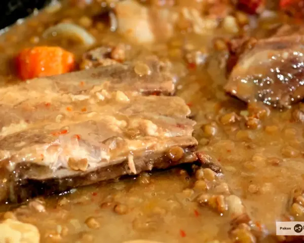 Guiso de lentejas con costillas, zanahoria y trozos de carne en un caldo espeso.