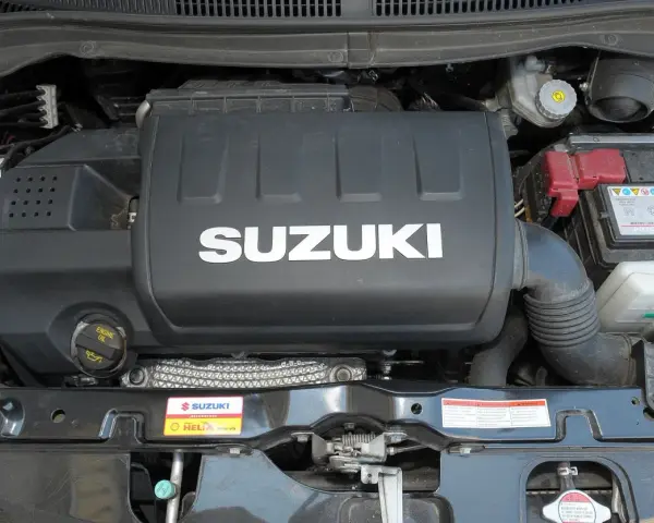 Silnik Suzuki Swift 2007 z widocznym logo SUZUKI na pokrywie. Widać akumulator i elementy układu dolotowego.