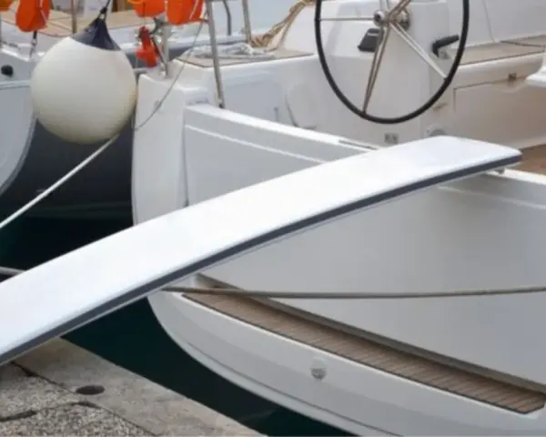 Eine selbstgebaute Gangway für Boote, die über eine Reling gelegt wird.