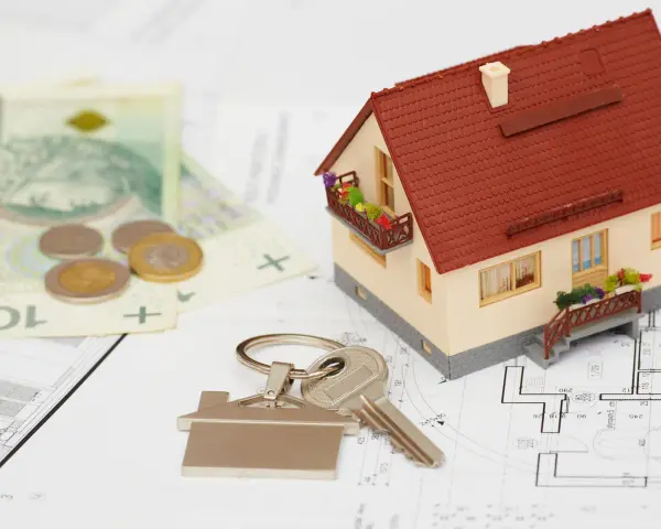 Model domu, klucze, pieniądze i plany architektoniczne.