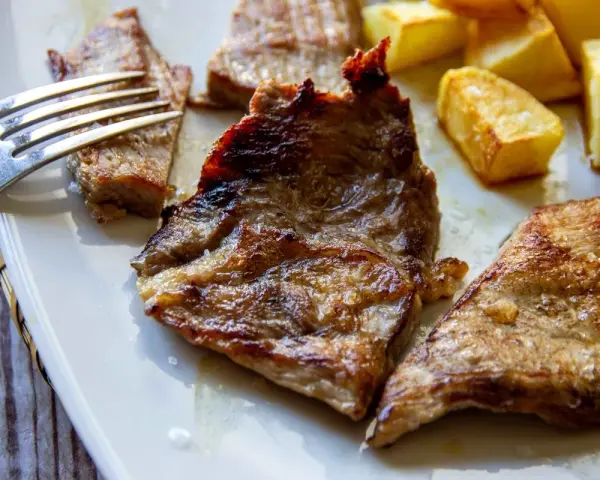 Jugosa blanqueta de cerdo a la plancha, servida con patatas fritas doradas. Un plato perfecto para disfrutar.