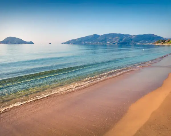 Spokojna plaża Caretta z łagodnymi falami i wyspami w oddali. Idealne miejsce na relaks.