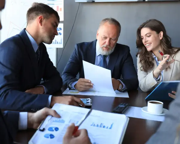 Team discusses broker-dealer compliance, reviewing charts and documents in a meeting.