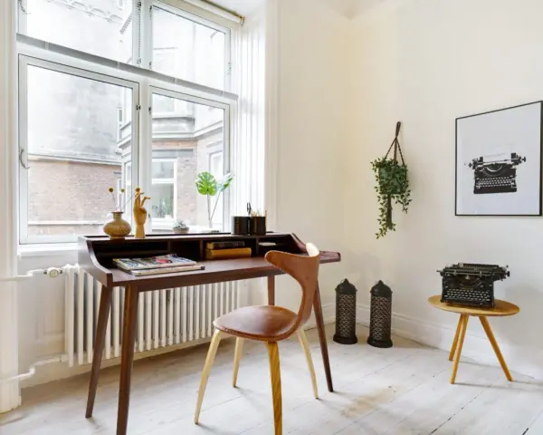 Ett elegant skrivbord i oljad ek med en läderklädd stol. En gammal skrivmaskin står på ett litet sidobord.