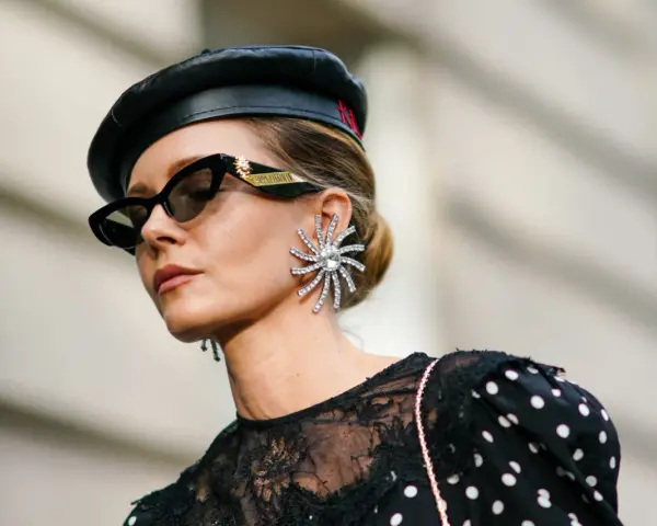 Kobieta w czarnym beretce i okularach przeciwsłonecznych, z dużą, błyszczącą kolczykiem. Czy grochy są modne? Ta stylizacja sugeruje, że tak!