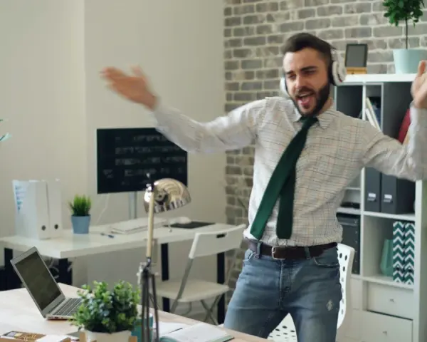 Mężczyzna z **ENFP osobowością** tańczy w biurze, słuchając muzyki na słuchawkach.