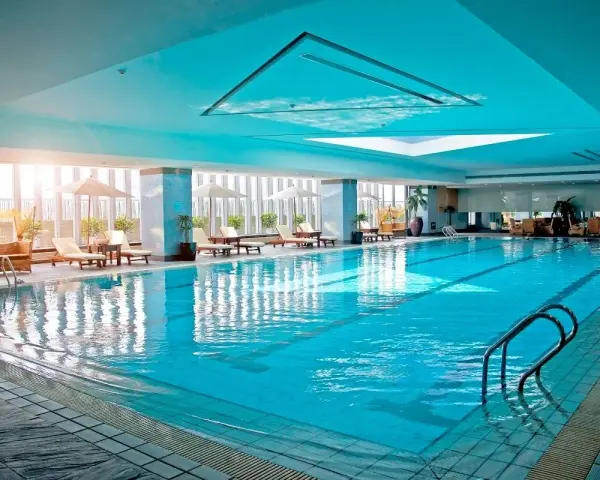 Relaks w hotelu z basenem na Podlasiu. Długi, błękitny basen z leżakami i parasolami, idealny na wakacje.