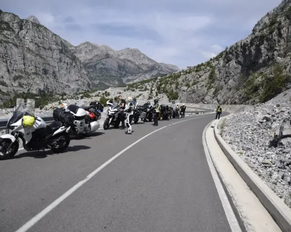 Grupa motocyklistów zatrzymała się na malowniczej drodze w Albanii, podziwiając spektakularne widoki gór.