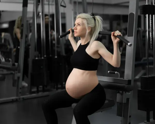 Gravid kvinna tränar marklyft i gym.