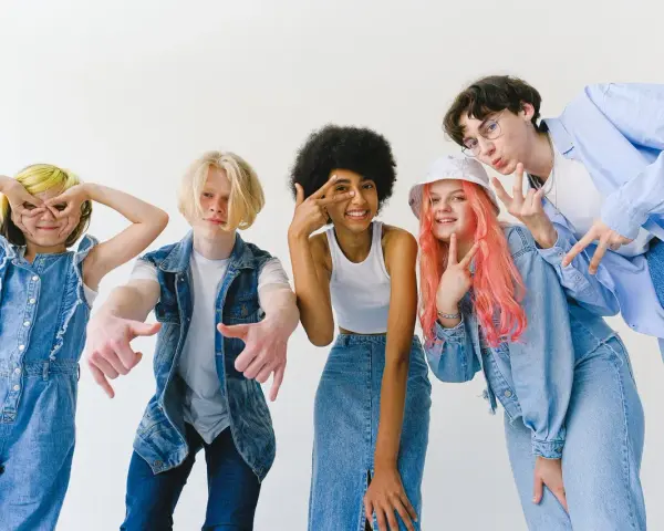Ragazzi con un look anni '90, tutti vestiti di jeans, fanno pose divertenti.