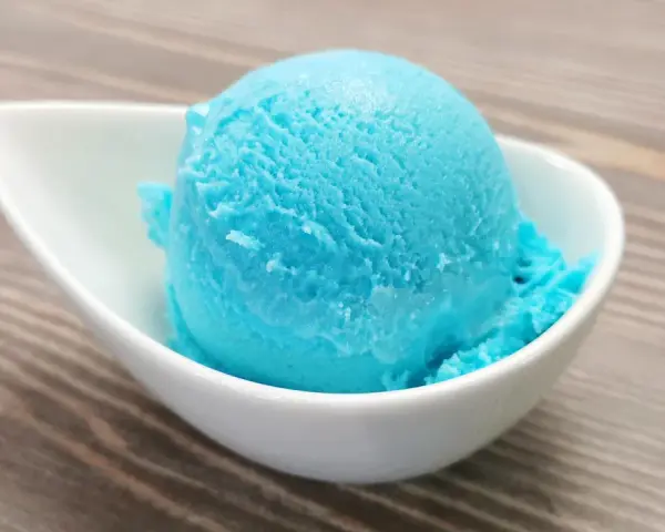 Ein Löffel leuchtend blaues Kaugummi Eis in einer weißen Schale. Perfekt für ein selbstgemachtes Kaugummi Eis Rezept.