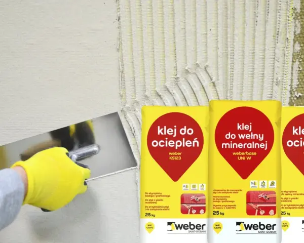 Rękawica w żółtej rękawicy nakłada klej na ścianę. Obok worki z napisem "klej do ociepleń" – idealny, by przykleić styropian do blachy.