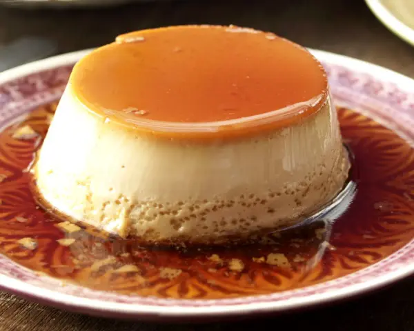 Delicioso flan de café con caramelo líquido, servido en un plato con un diseño intrincado.