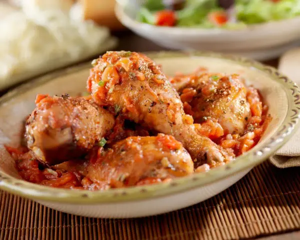 Pollo guisado en salsa de tomate y especias en un cuenco.