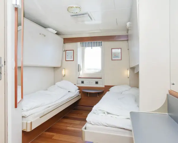 Przytulna stena spirit kabiny z dwoma łóżkami, oknem i szafkami.