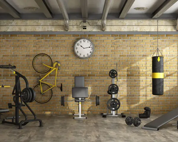 Ett välutrustat gym i garaget med vikter, boxningssäck, cykel och träningsbänk.