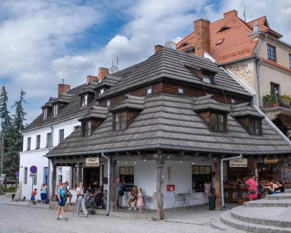 Kazimierz Dolny rynek tętni życiem. Ludzie spacerują, kupują lody i gofry pod urokliwymi, drewnianymi dachami kamienic.