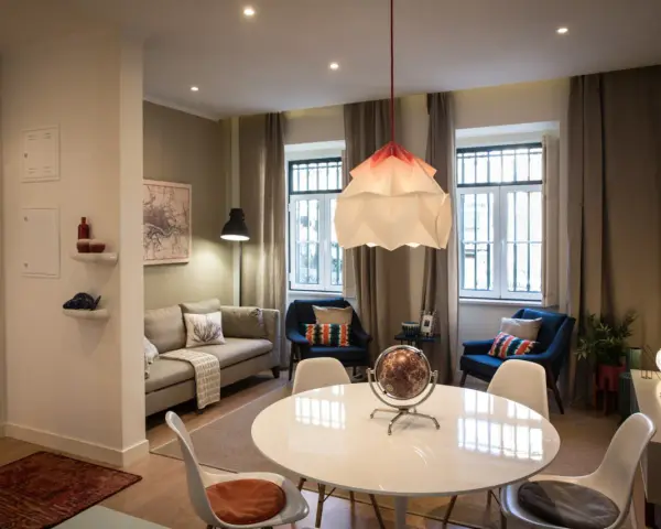 Una sala da pranzo moderna con tavolo bianco, sedie, divano, poltrone blu e un globo decorativo.