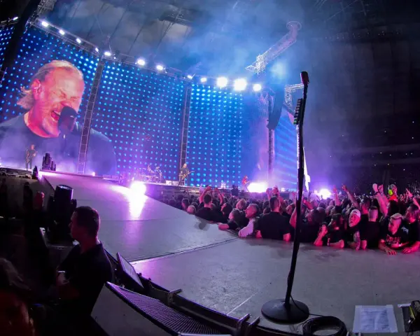 James Hetfield śpiewa na koncercie Metalliki w Warszawie. Tłum szaleje, a gigantyczny ekran pokazuje zbliżenie na wokalistę.