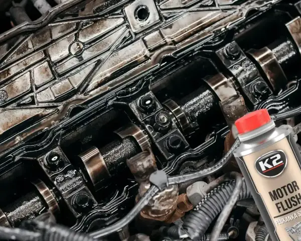 Zanieczyszczony silnik benzynowy i butelka K2 Motor Flush – najlepsza płukanka do silnika benzynowego, która przywróci mu czystość i moc.