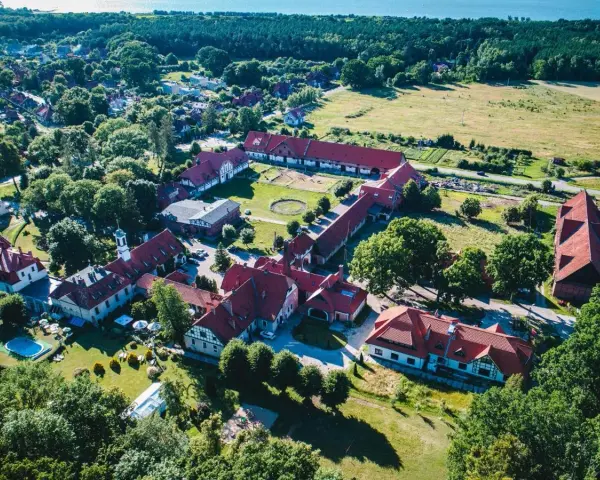 Widok z lotu ptaka na kompleks budynków hotelowych z czerwonymi dachami. Wiele pozytywnych kadyny folwark hotel & spa opinie potwierdza urok tego miejsca.