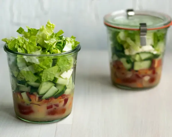Frischer Salat im Glas, perfekt für eine Party. Schichten aus knackigem Salat, Gurken und Tomaten mit Dressing.