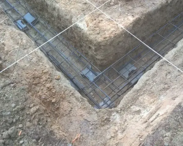 Zbrojenie fundamentów prefabrykowanych w wykopie. Stalowe pręty tworzą siatkę, gotową do zalania betonem.