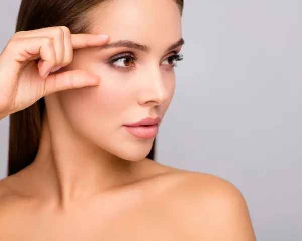 Kobieta bada swoją skórę, która po zabiegu skin booster jest nawilżona i promienna.