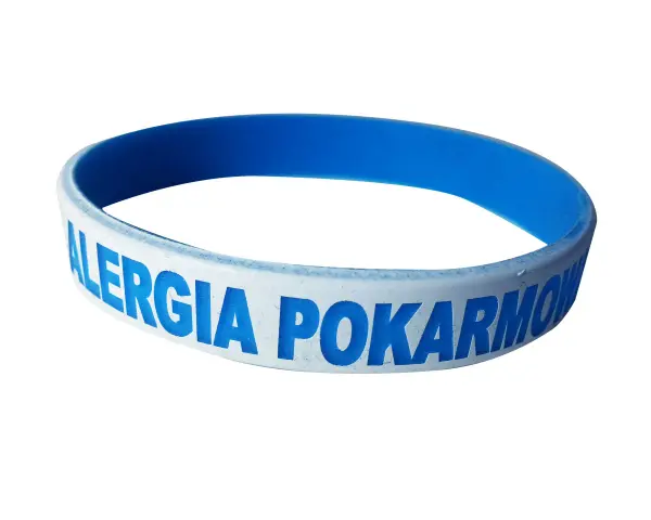 Niebieska opaska na ręce z napisem "ALERGIA POKARMOWA" informuje o problemach z jedzeniem.