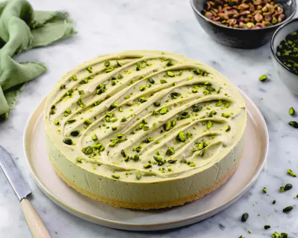 Cheesecake al pistacchio cremosa, decorata con granella verde brillante. Un dolce invitante pronto per essere gustato.