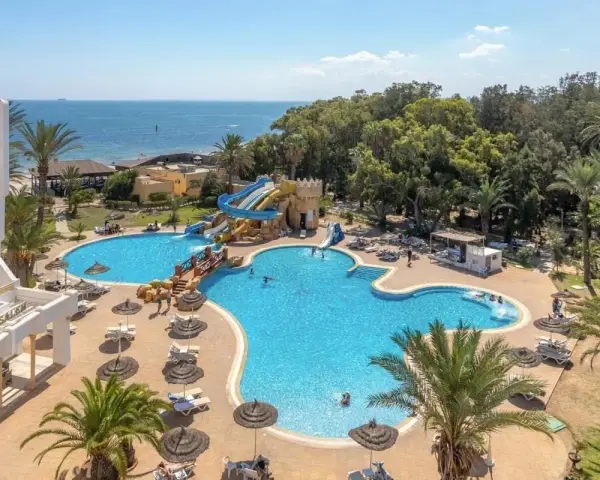 Hotel Marhaba Royal Salem kusi basenem z wodnymi zjeżdżalniami i palmami, w tle morze.