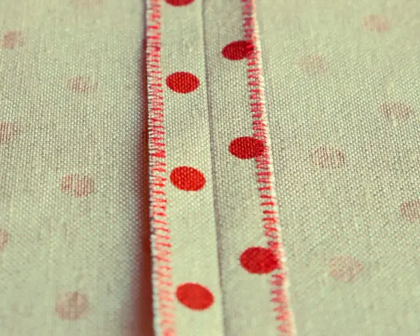 Tessuto a pois rossi con cucitura a punto sopraggitto a mano che crea un dettaglio decorativo.