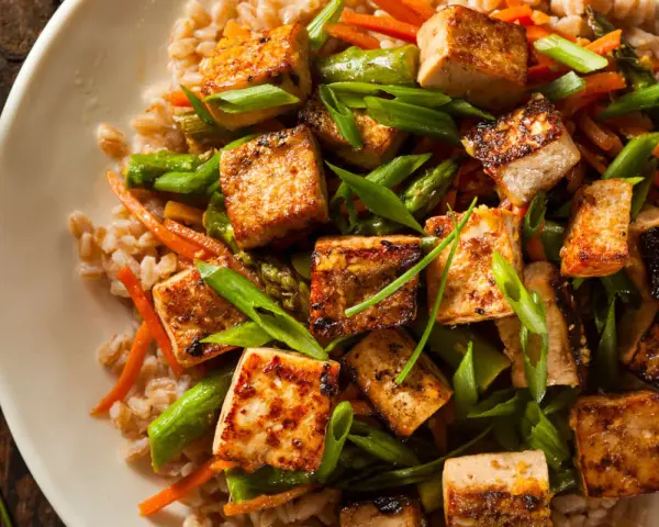 Chrupiące kostki tofu z warzywami i kaszą. Tofu to wszechstronny produkt roślinny, idealny do dań azjatyckich.