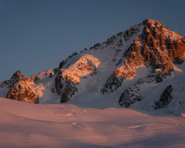 Ośnieżone szczyty Alp o wschodzie słońca, oświetlone złotym blaskiem. Widok na trasę Haute Route, gdzie lodowce i skaliste zbocza tworzą majestatyczny krajobraz.
