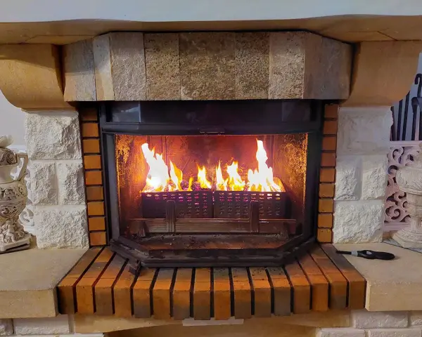 Chimenea de leña con llamas vibrantes. El fuego ilumina el interior de la chimenea, creando un ambiente acogedor. Los pellets en la base de la chimenea se queman, alimentando las llamas.