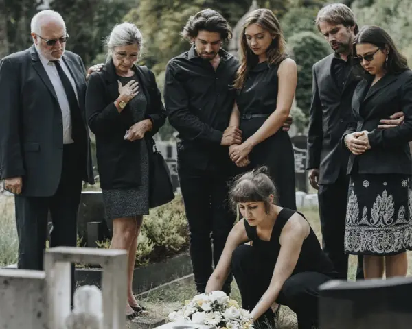 Famiglia in lutto, vestiti di nero, si riunisce al cimitero. Un esempio di come vestirsi a un funerale, con abiti sobri e rispettosi.
