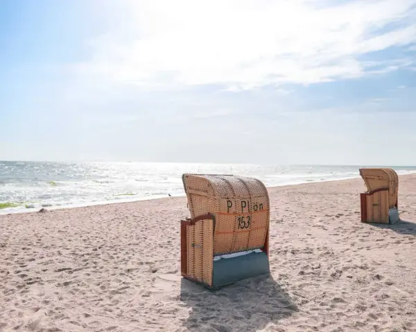 Strandkörbe am Dahme Strand unter blauem Himmel. Das Meer glitzert in der Sonne.