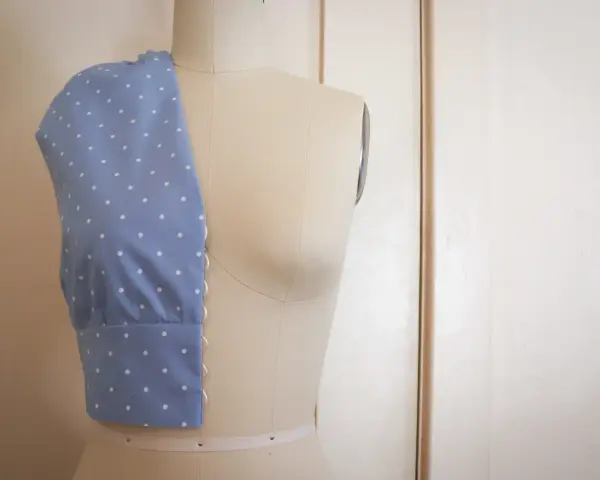 Mannequin de couture présentant un corsage bleu à pois blancs, esquisse d'une future robe de mariée couture.