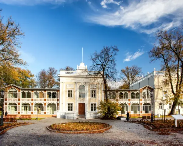 Brzeźno dom zdrojowy, zabytkowy budynek z arkadowymi werandami, otoczony jesiennym parkiem.