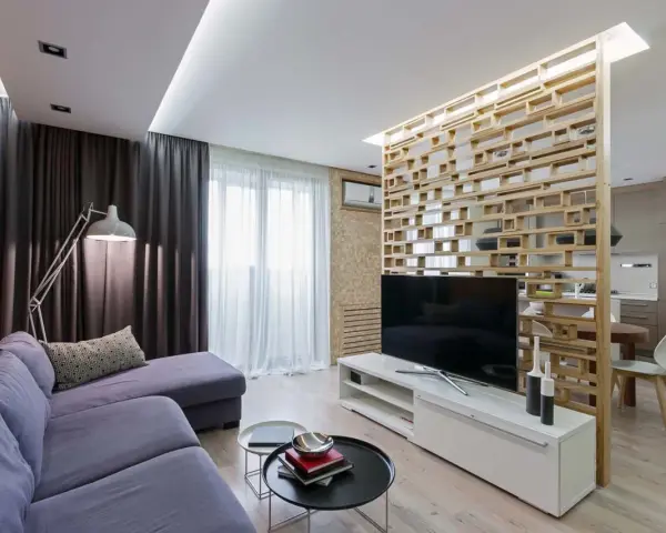 Acogedor salón de 18 metros cuadrados con sofá morado, lámpara de pie y separador de ambiente de madera.