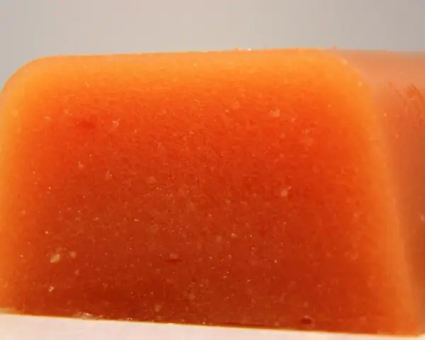 Bloque naranja de carne de membrillo, con textura granulada y bordes redondeados.