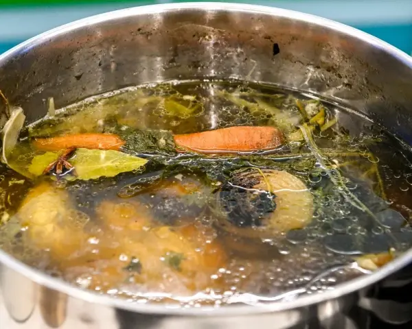 Bulion warzywny, idealny do przepisu na makaron domowy Ewy Wachowicz. Marchewka, liść laurowy i gwiazdka anyżu unoszą się w aromatycznym wywarze.