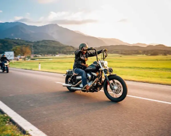 Motociclista in viaggio su una strada panoramica, un'atmosfera da European Bike Week con montagne sullo sfondo.