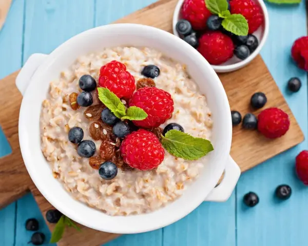 Un tazón de avena con frambuesas, arándanos y pasas. ¡Cuidado! La avena engorda si no se consume con moderación.